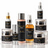 A collection of IKNOW skincare products arranged on a reflective white surface against a white background, including bottles, jars, and a pump bottle with black labels and silver and gold caps.